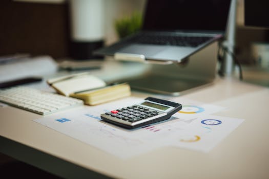 A modern workspace with a laptop, calculator, and documents on a desk, perfect for finance tasks.